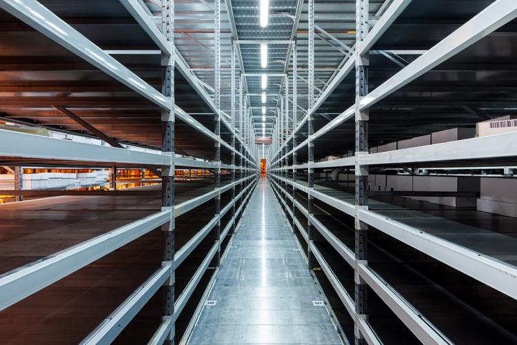 Looking down a well-lit warehouse aisle with empty shelving.